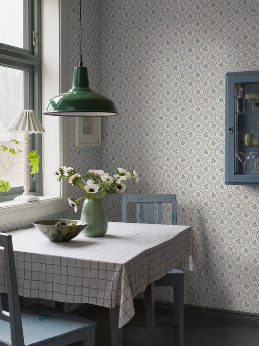 Set on a warm white background with delicate blue flowers and winding trellises, our Idun wallpaper takes its inspiration from traditional embroidery.