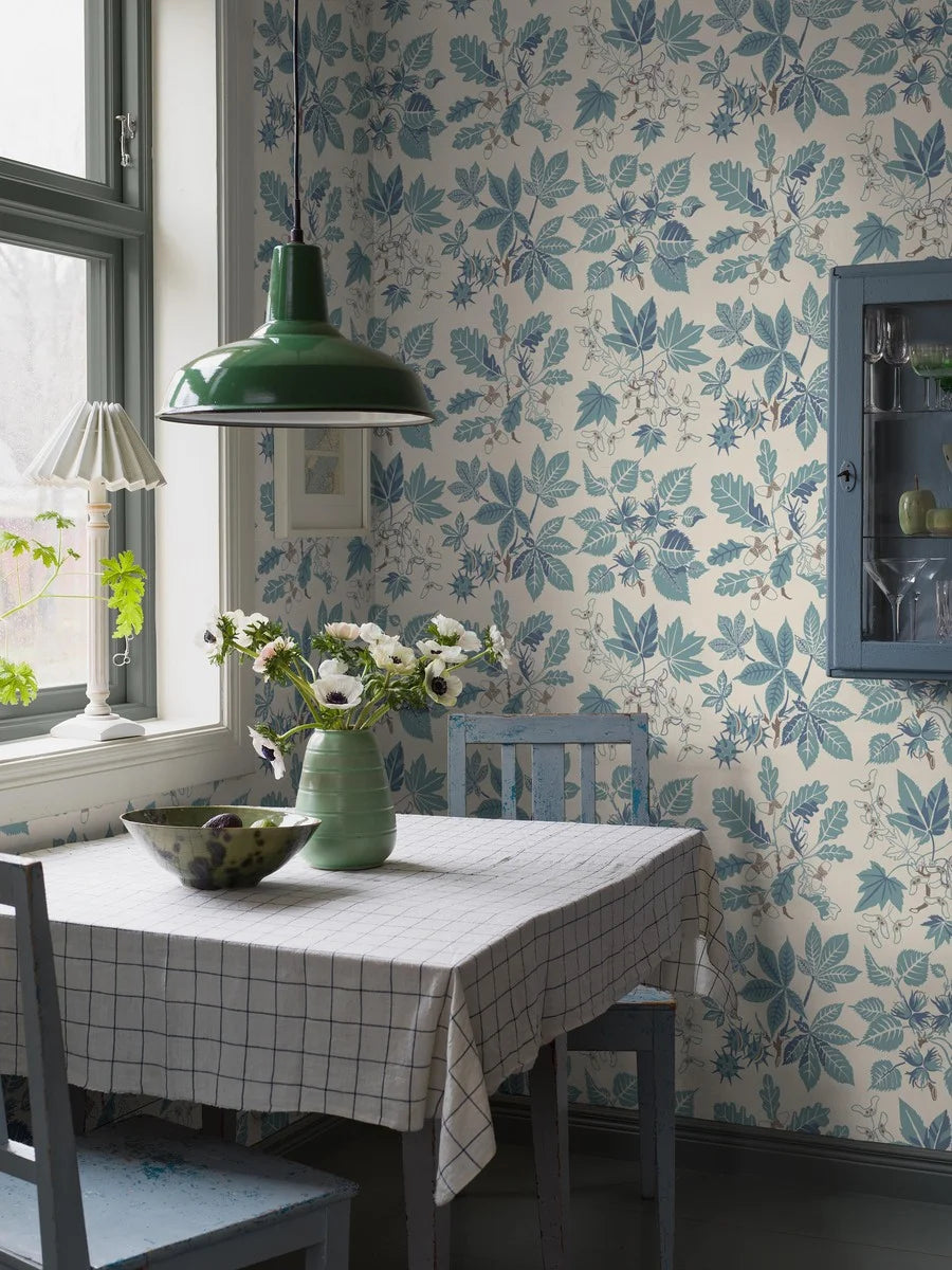 Colored in turquoise and warm blue tones accented with brown details on a warm white background, our Arboretum wallpaper transports you to a whimsical world.