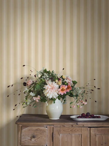 This Gunnebo wallpaper showcases cream-colored stripes set against a soft yellow background and evokes the charm of Gustavian interiors.