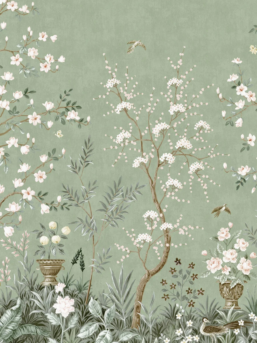 The green wallpaper Magnolia Garden is adorned with a lush, hand-painted pattern in classic chinoiserie style, featuring blooming trees, grand flower urns, and beautiful birds.