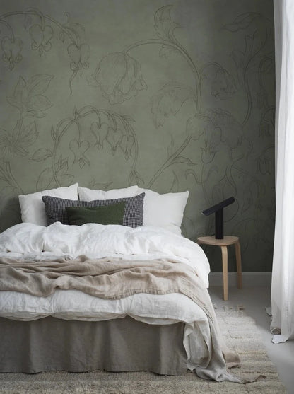 The green wallpaper Burning Heart is adorned with an airy, large-scale floral pattern of delicate bellflowers and bleeding hearts climbing towards the ceiling. 