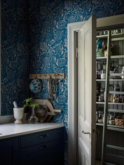 Wundervogel wallpaper in blue showcases whimsical birds and lush, winding plants in a large-scale pattern with modernist expressions evident in the pattern’s geometric and winding embellishments. 